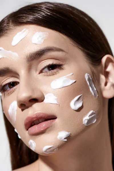 Une belle jeune femme embrassant avec confiance les soins de la peau avec une généreuse quantité de crème sur son visage. — Photo de stock