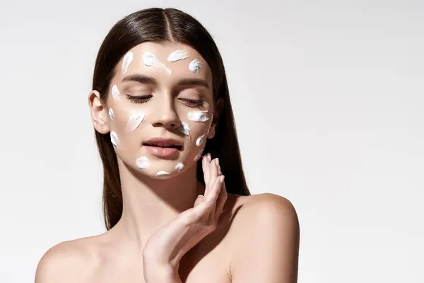 A captivating young woman with delicate white cream adorning her face, exuding beauty and grace. — Stock Photo