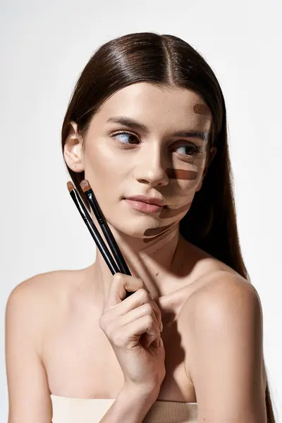 Uma mulher com maquiagem no rosto, segurando um pincel para aplicação cosmética. — Fotografia de Stock