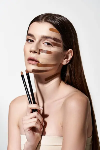 Young woman with makeup brushes and makeup strokes on her face, creating a creative and artistic look with foundation. — Stock Photo