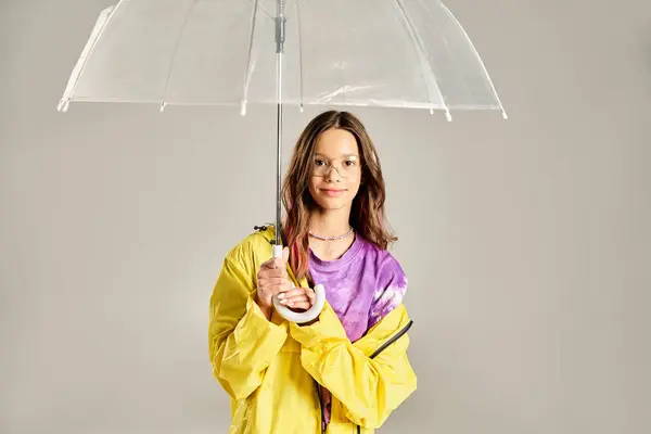 Une adolescente à la mode, portant un imperméable jaune vif, pose énergiquement avec un parapluie un jour de pluie. — Photo de stock