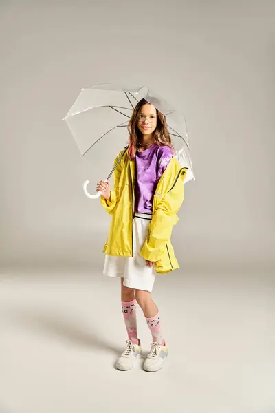 Teenagermädchen posiert in einem eleganten gelben Regenmantel mit einem bunten Regenschirm. — Stockfoto