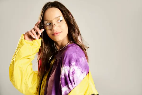A stylish teenage girl in a yellow and purple shirt actively talking on a cell phone. — Stock Photo