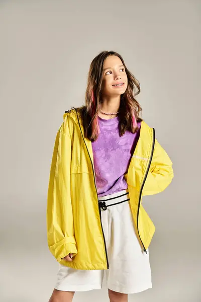Une adolescente à la mode prend une pose ludique dans une veste jaune vibrante et un short blanc, respirant la confiance et le style. — Photo de stock