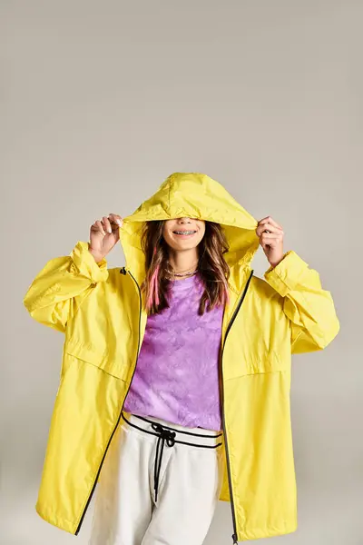 Ein stilvolles Teenager-Mädchen posiert energisch in gelber Jacke und weißer Hose und strahlt Selbstbewusstsein und Eleganz aus. — Stockfoto