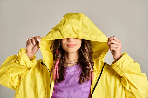 Девочка-подросток в жёлтом плаще закрывает лицо руками в оживлённой позе.. — стоковое фото