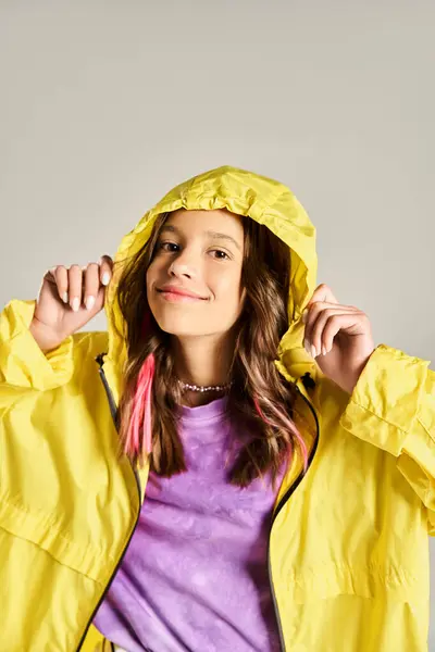 Ein stilvolles Teenager-Mädchen posiert aktiv in einem leuchtend gelben Regenmantel, der an einem sonnigen Tag Lebendigkeit und Energie ausstrahlt. — Stockfoto