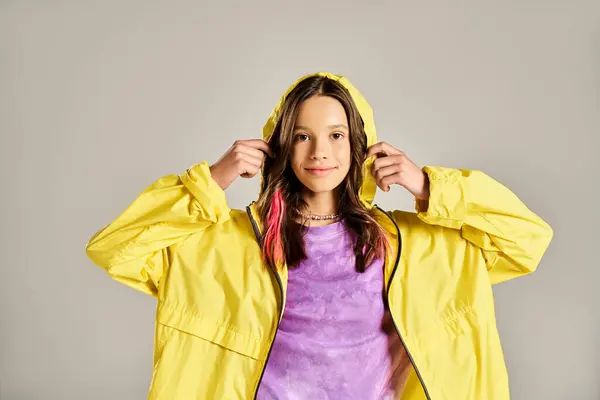 A stylish teenager in a vibrant yellow raincoat striking a pose for the camera with energy and confidence. — Photo de stock