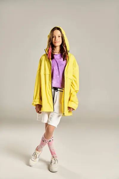 Ein modisches Teenager-Mädchen posiert in einem leuchtend gelben Regenmantel, der Stil und Energie ausstrahlt. — Stockfoto