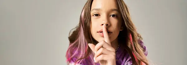 Une adolescente élégante aux cheveux longs tenant son doigt sur ses lèvres dans un geste secret. — Photo de stock