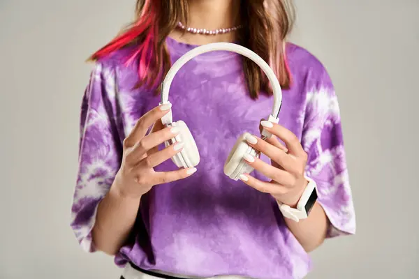 A stylish teenage girl energetically holds a pair of headphones in her hands. — Stock Photo