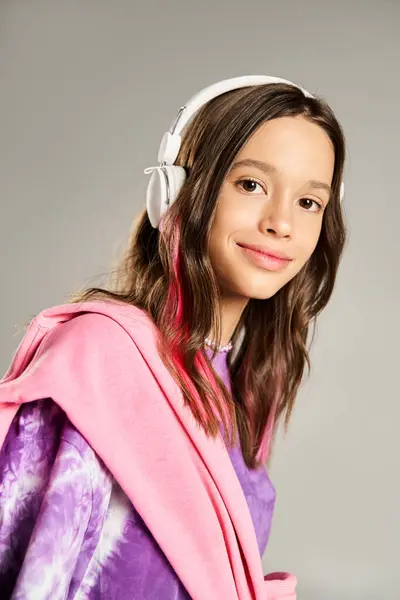 Стильна дівчина-підліток в халаті насолоджується своєю музикою через навушники, демонструючи яскраву енергію і спокій. — стокове фото