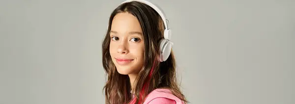 A stylish teenage girl in a vibrant pink shirt poses with headphones on, exuding a lively and fashionable vibe. — Stock Photo
