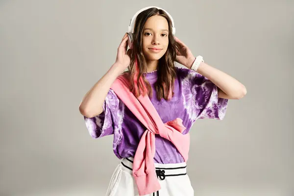 Une adolescente élégante dans une chemise violette vibrante portant des écouteurs, posant activement. — Photo de stock