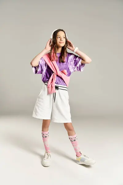 Uma menina adolescente elegante posa ativamente em uma camisa roxa e shorts brancos. — Fotografia de Stock