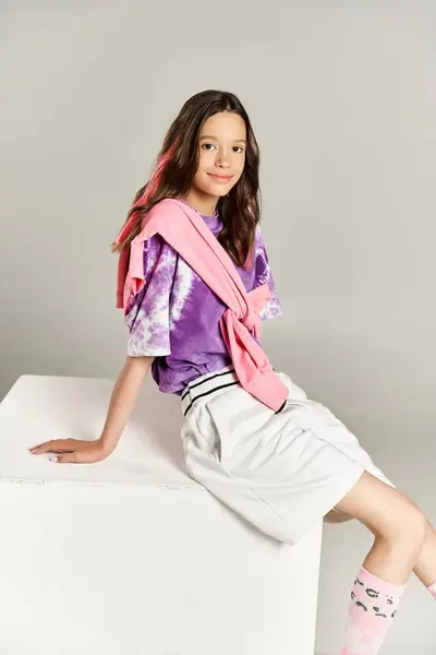 Uma menina adolescente elegante e vibrante marcando uma pose enquanto se senta em cima de uma caixa branca. — Fotografia de Stock