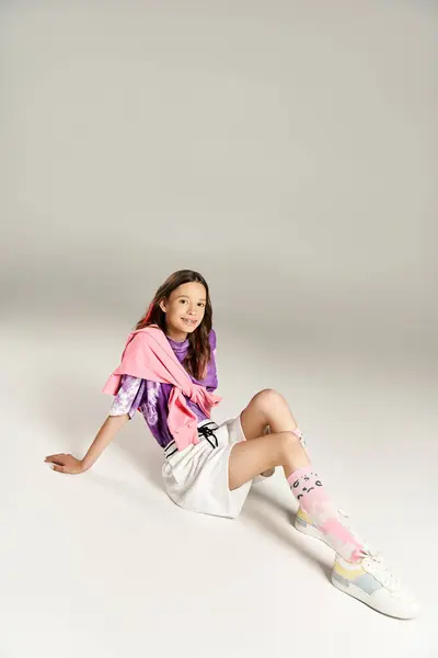 Стильная, энергичная девушка-подросток сидит на земле, скрестив ноги, участвуя в активном созерцании. — стоковое фото