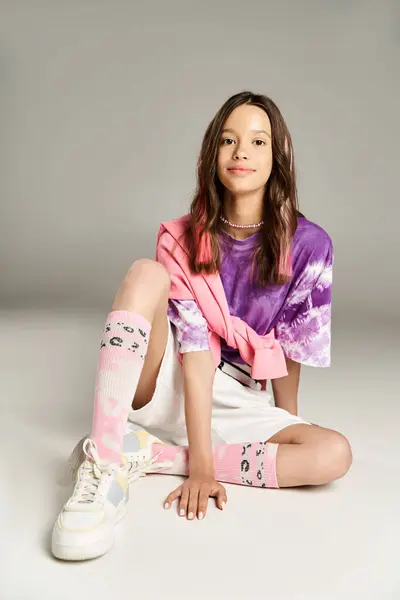 Ein Teenager-Mädchen in lebendiger Kleidung sitzt im Schneidersitz auf dem Boden und strahlt Gelassenheit und Anmut aus. — Stockfoto