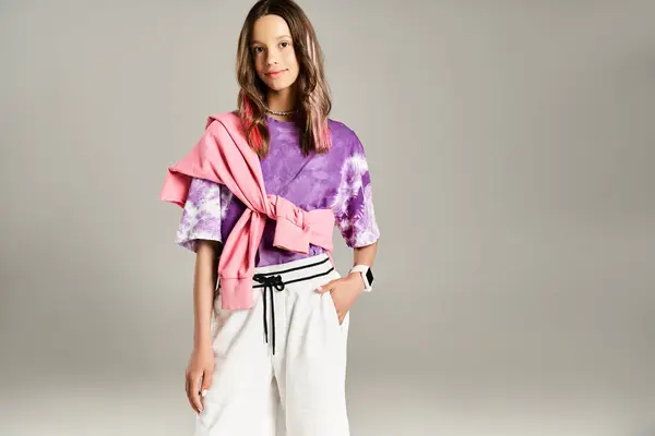 Una adolescente de buen aspecto alcanza una pose dinámica con un atuendo elegante, con una camisa púrpura y pantalones blancos. - foto de stock