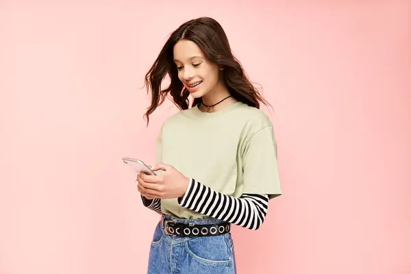 Ein stilvolles Teenie-Mädchen in einem leuchtend grünen Hemd, das sich auf ihren Handy-Bildschirm konzentriert. — Stockfoto
