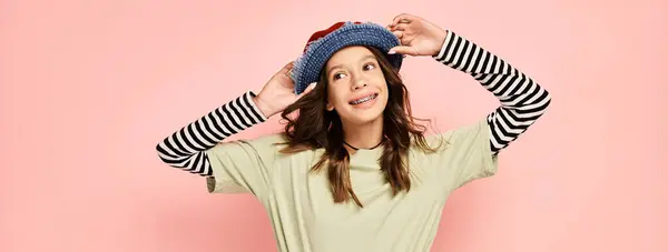 A good looking teenage girl in vibrant attire, energetically posing with a stylish hat on her head. — Stock Photo