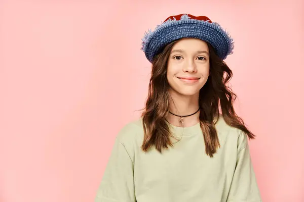 A stylish teenage girl poses energetically in a blue hat and green shirt. — Stock Photo