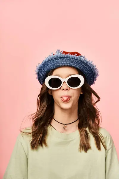 Uma menina adolescente elegante vestindo óculos de sol e um chapéu, fazendo uma expressão humorística. — Fotografia de Stock