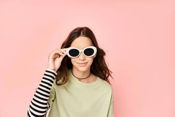 Ein modisches Teenager-Mädchen posiert energisch in grünem Hemd und stylischer Sonnenbrille und strahlt Selbstbewusstsein und Stil aus. — Stockfoto