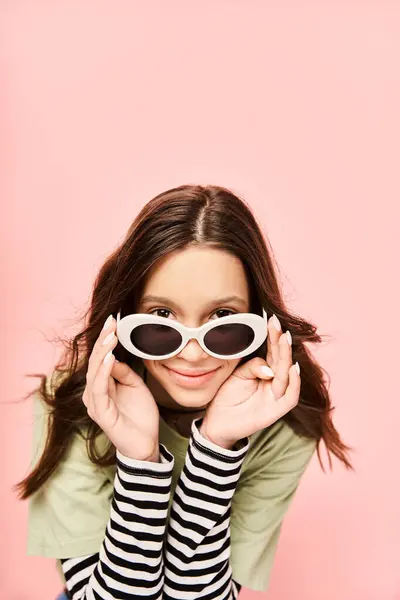 Une adolescente à la mode en tenue vibrante pose avec confiance avec des lunettes de soleil sur son visage. — Photo de stock