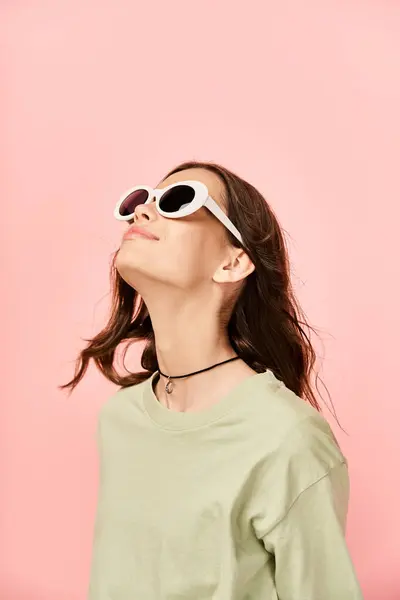 Uma jovem na moda em trajes vibrantes, usando óculos escuros, olha atentamente para o céu. — Fotografia de Stock