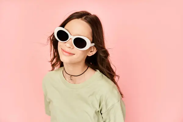 Uma menina elegante faz uma pose em trajes vibrantes, balançando um par de óculos de sol redondos com toque. — Fotografia de Stock