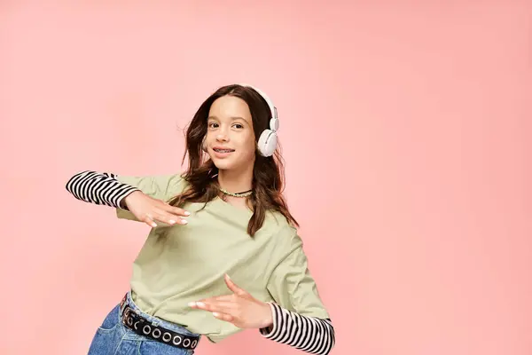 Une adolescente élégante dans une chemise verte écoute attentivement la musique à travers des écouteurs, exsudant une aura vibrante et captivante. — Photo de stock