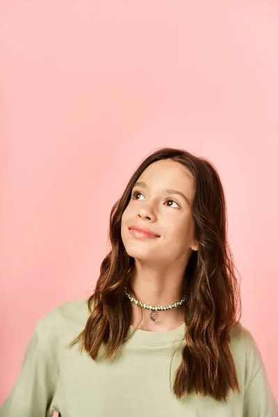 A fashionable teenage girl strikes a pose in front of a brightly colored pink wall with confidence and style. - foto de stock