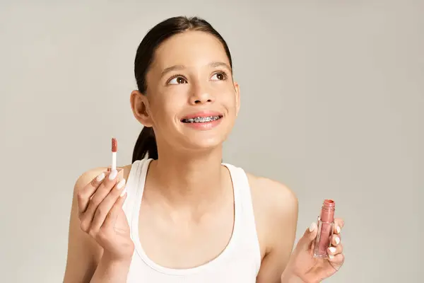 Стильная девушка-подросток держит бальзам для губ, готовясь к стоматологической процедуре с ярким чутьем. — стоковое фото