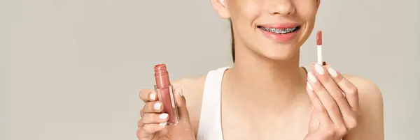 Une adolescente élégante tenant du rouge à lèvres dans une tenue vibrante, mettant en valeur sa personnalité ludique et active. — Photo de stock