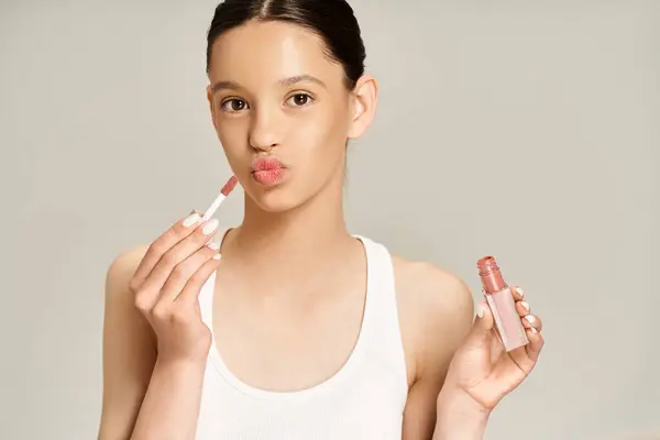Stylish teenage girl holds two lip balms in her hands, exuding confidence and charm in vibrant attire. — Stock Photo