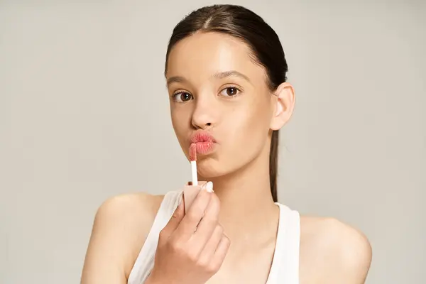 Une adolescente élégante et vibrante tient un baume à lèvres dans sa main droite, exsudant élégance et assurance. — Photo de stock