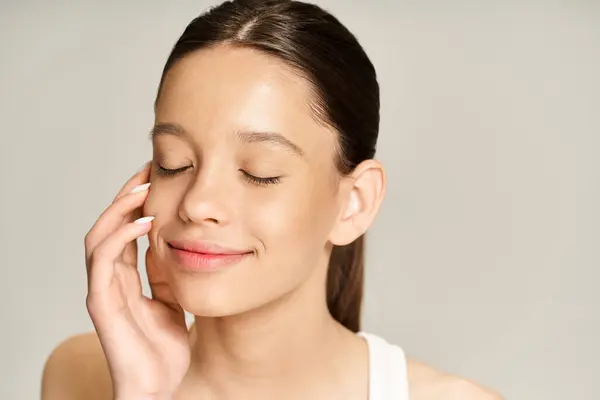 Una elegante adolescente con los ojos cerrados, sosteniendo su mano al oído en un sereno momento de conexión. - foto de stock