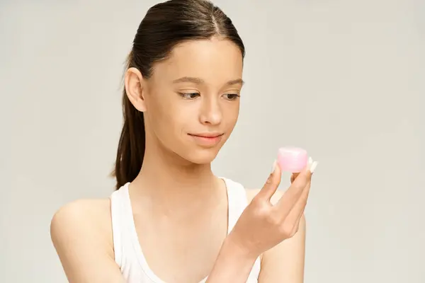Une adolescente élégante en tenue vibrante tenant une crème rose avec une expression captivante. — Photo de stock