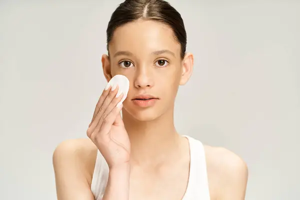 Trendy teenage girl in vibrant attire holds cotton pad in front of her face, exuding a mysterious allure. — Stock Photo