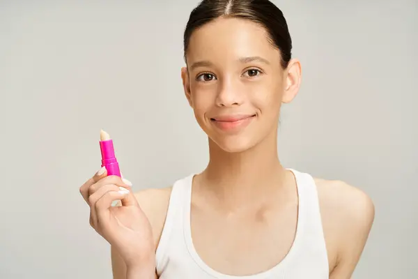 Elegante adolescente en ropa de moda tiene un lápiz labial rosa en la mano. - foto de stock