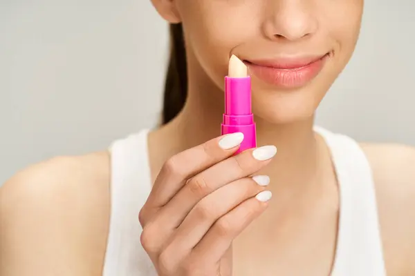 Teenage girl in stylish attire, energetically holds a lip balm, showcasing beauty and confidence. — Stock Photo