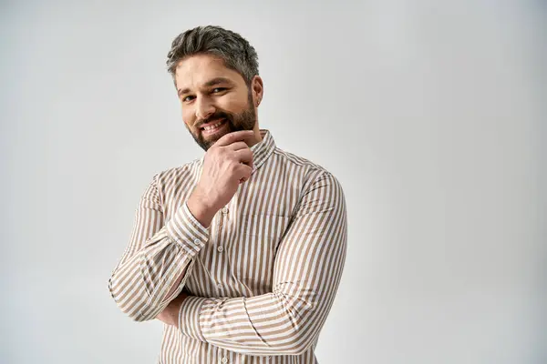 A stylish man with a beard poses in elegant attire against a grey background in a studio setting. — Stock Photo