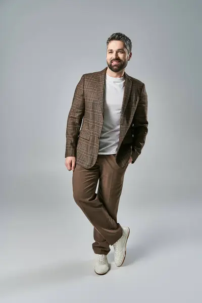 A bearded man in elegant attire strikes a pose in front of a gray background, exuding charisma and style. — Stock Photo