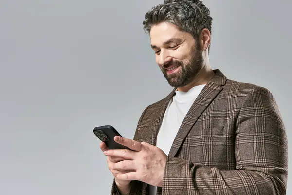 Ein stilvoller Mann im Anzug starrt gespannt auf sein Handy, verloren in Gedanken. — Stockfoto