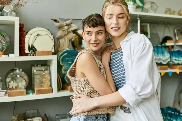 A loving lesbian couple, two women, standing in an art studio with a tender connection. — Stock Photo