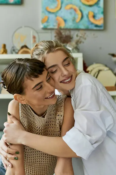 Due donne, una coppia lesbica amorevole, condividono un tenero abbraccio in uno studio d'arte. — Foto stock