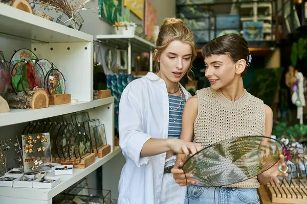 Dos mujeres admirando un jarrón de cristal en un estudio de arte. - foto de stock