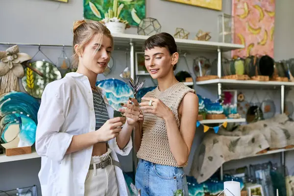 Two women, one with short hair and the other with long hair, closely inspecting a decorative plate in a boutique. — Stock Photo