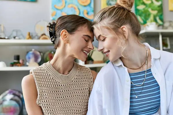 Two women, a loving, tender lesbian couple, stand next to each other in an art studio. — Stock Photo